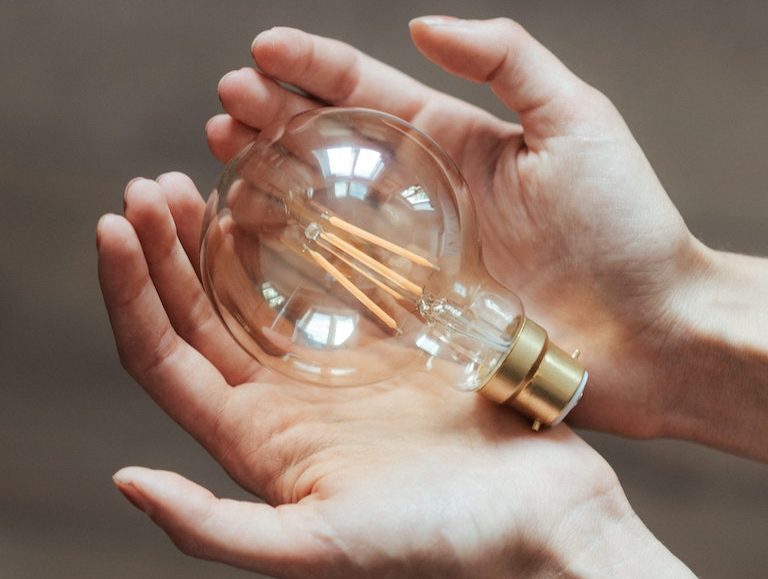 Unrecognizable woman demonstrating light bulb in hands